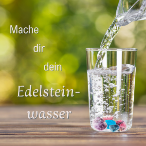 Aus einer Glaskaraffe wird Wasser in ein Glas mit Heilsteinen eingeschenkt
