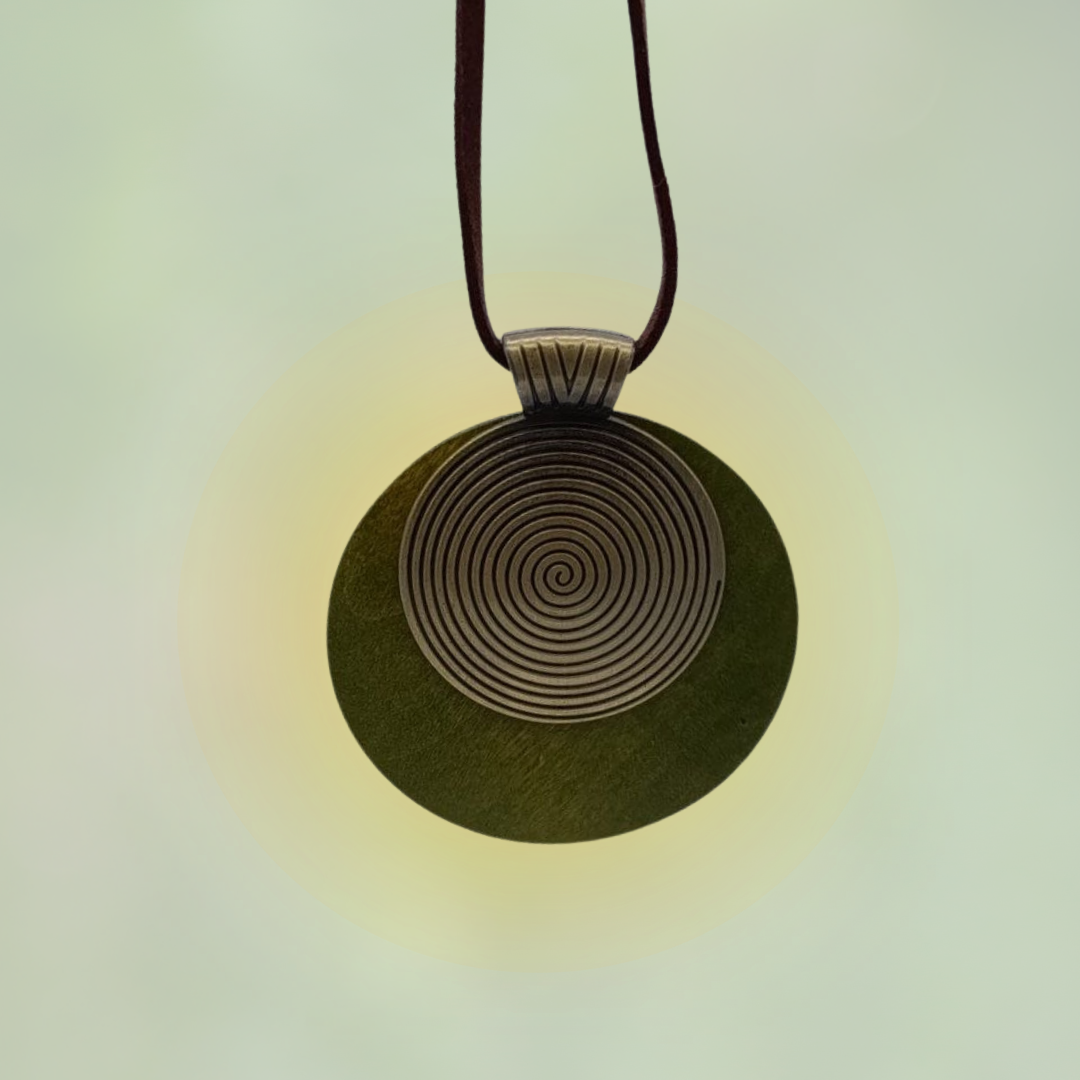 Kette aus Holz mit einer feinen Metallplatte und linksdrehender Spirale, getragen an einem weichen Lederband.