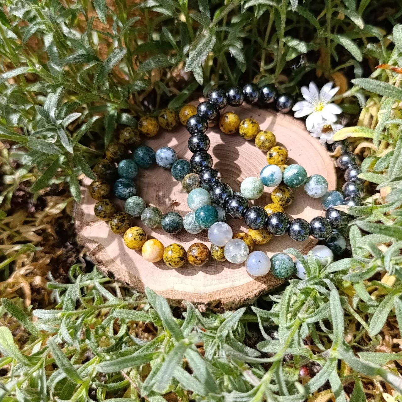 3 Edessteinarmbänder auf einer Holzschiebe 
